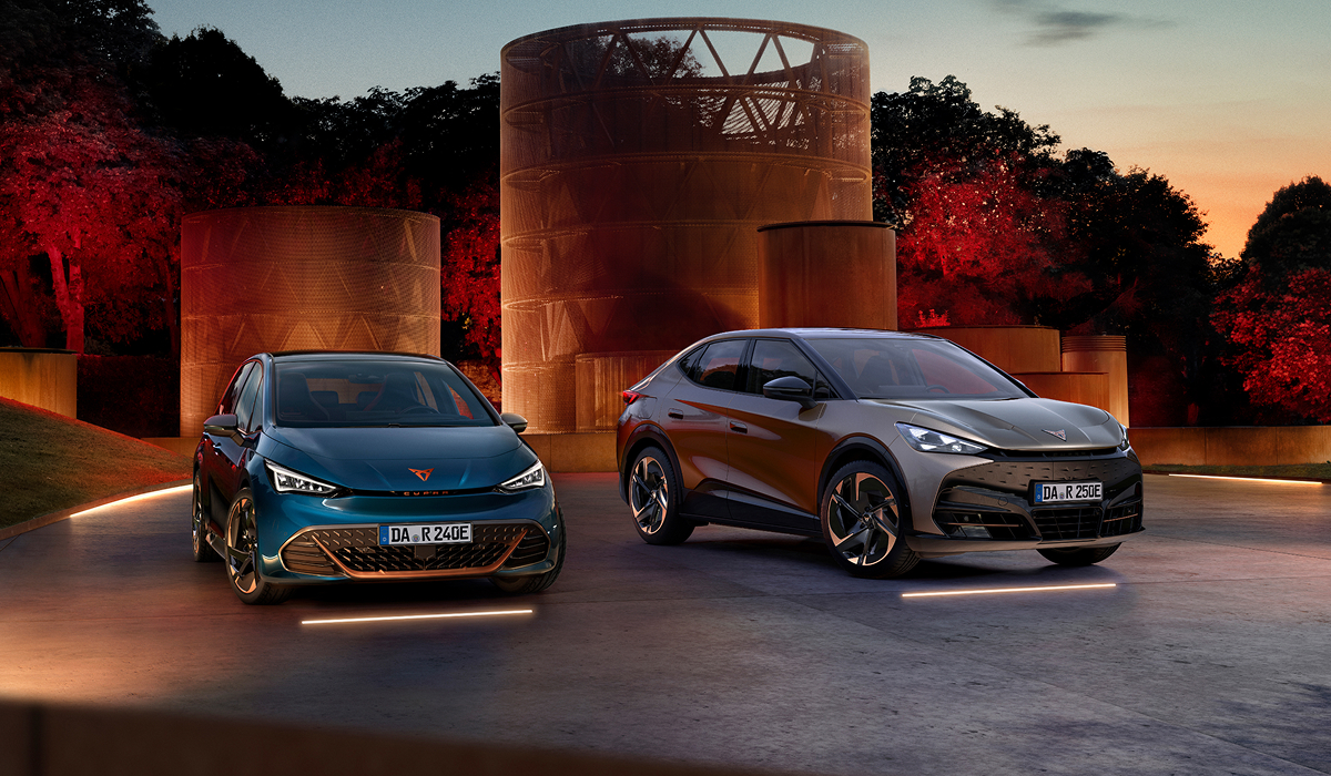 Ein blauer CUPRA Born steht neben einem grauen CUPRA Tavascan, beide Modelle vor rot beleuchteter Architektur bei Nacht.